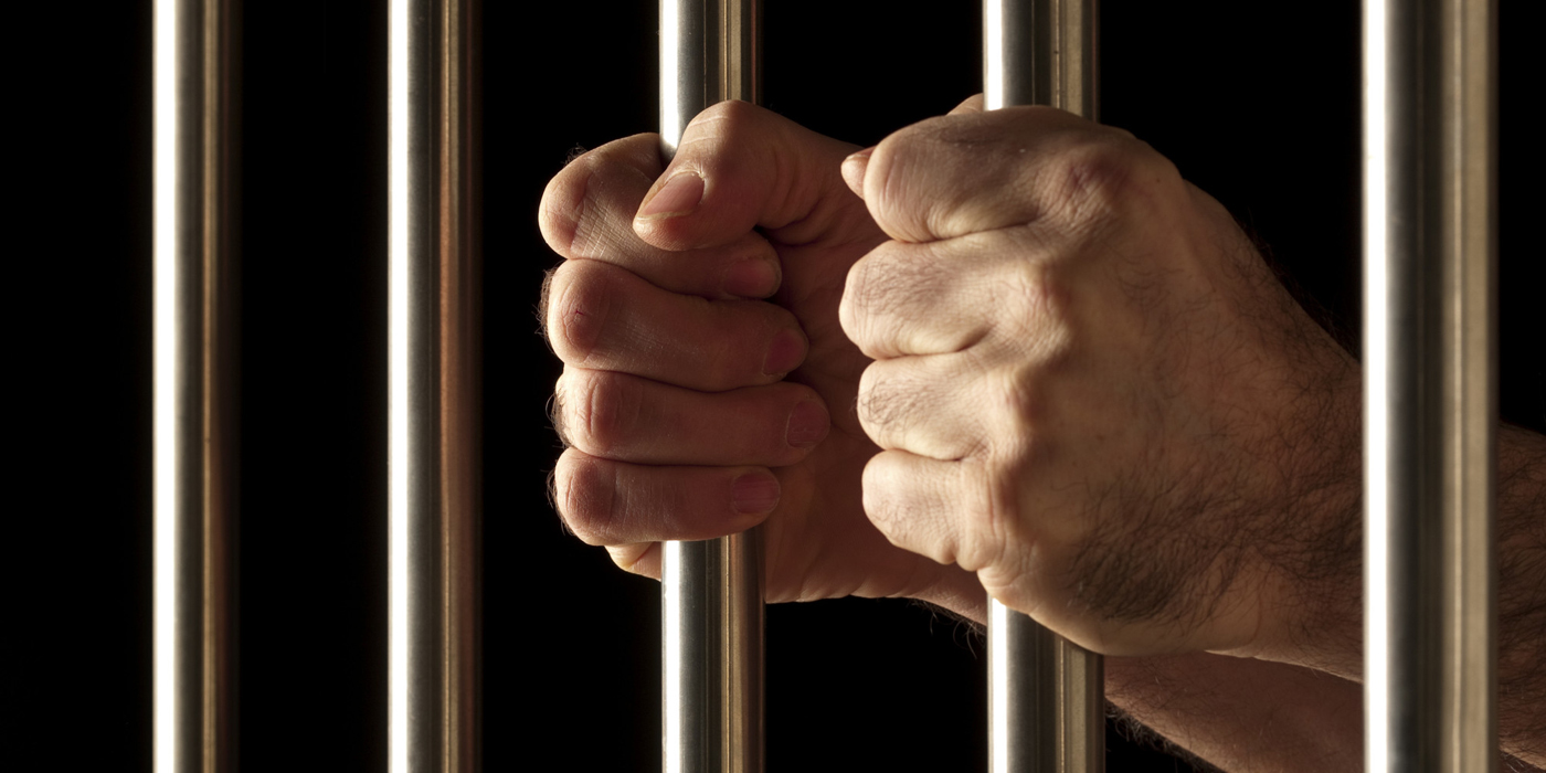 Hands gripping jail bars — R3 Bail Bonds gets you out fast